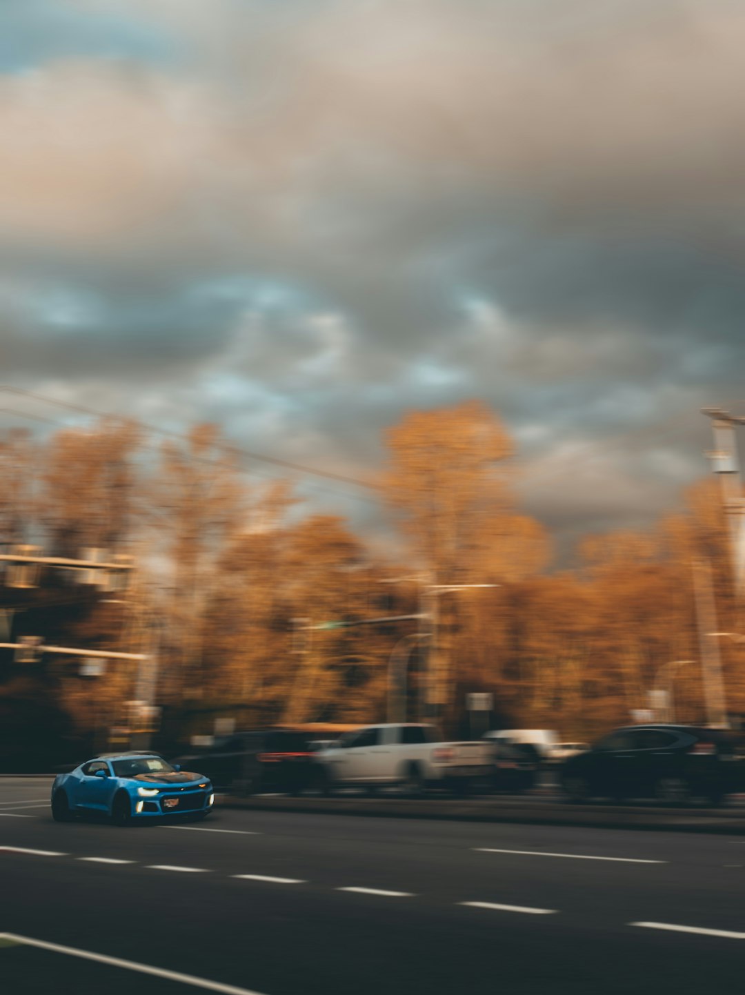 a blue car driving down a street next to tall buildings