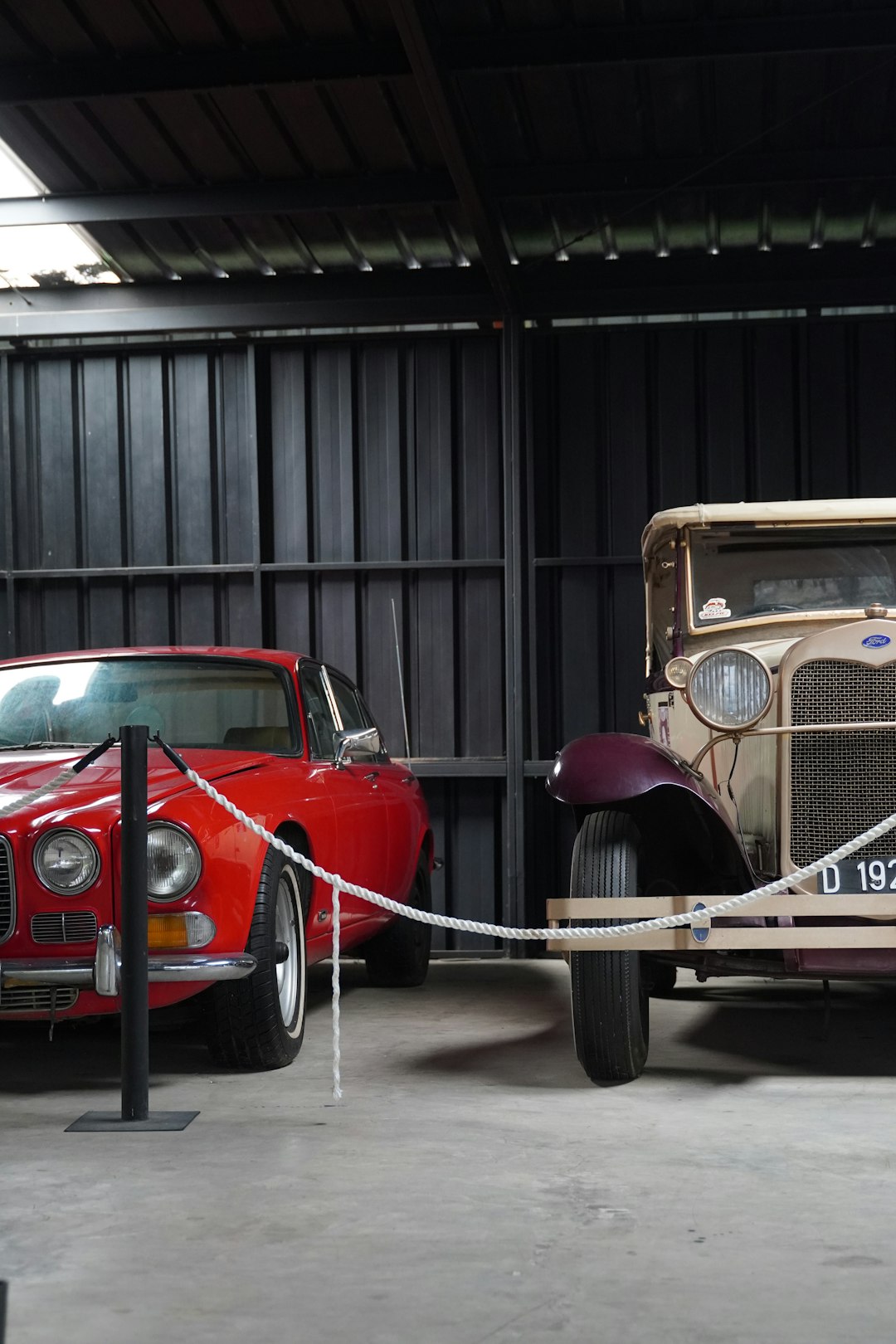 Two old cars parked in a garage next to each other
